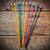 Knitters Pride Dreamz 10" and 14" wooden knitting needles set with assorted colors, manufactured by Knitters Pride, on a rustic wooden background.