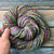 Handspun, hand dyed merino wool yarn, multicolor, vibrant, soft, warm, durable, 100% pure wool, in a skein on a wooden background.