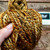 Handspun Superwash Merino Wool Yarn in Golden Sand, a mix of yellow, orange, brown, and cream colored yarn in a skein.