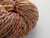 Luxury handspun Merino wool skein in warm autumn tones, 2-ply sport/DK weight yarn with subtle multicolored flecks, soft and earthy color palette.