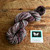 Luxury handmade Merino wool yarn, Midnight Bloom from brand Forever Winding Wool, featuring multicolored purple, pink, and gray hues on a wooden surface with branded logo.