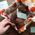 Luxury Handspun Merino yarn, 2-ply Sport/DK wool in autumnal colors, neatly arranged in a box with fall-themed tissue paper and product tags.