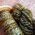 Luxury Merino wool yarn skeins in Mountain Twilight, green, orange, and blue hues, light worsted weight DK, handmade, showcasing earthy tones.