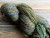 Luxury handspun Merino wool yarn in Reflection, a limited edition Monet colorway by Forever Winding Wool, featuring a multicolored blend of green, blue, and yellow hues.