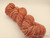 Soft peach and rose-colored skein of Luxury Handspun Merino yarn, Artisan 2-Ply Sport/DK wool, showcasing gentle peach rose elegance in a delicate color blend.