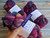 Malabrigo Nube Boreal, 100% Merino Wool Roving, multicolored yarn skeins in purple, pink, and blue hues, labeled "Nube" and "Boreal".