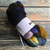 Malabrigo Nube Candombe merino wool roving, 4oz, multicolored yarn bundle with shades of purple, blue, green, and yellow, wrapped in white label.