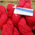 Malabrigo Worsted Geranio, vibrant red hand-dyed merino yarn skeins with label reading 044 Geranio, showcasing bold color and textured yarn.
