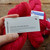 Malabrigo Worsted Geranio yarn, vibrant red hand-dyed merino wool skeins with brand tag and care label, displayed on rustic wooden surface.