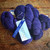 Malabrigo Worsted Violetas purple hand-dyed merino wool yarn skeins with label and tag on a wooden surface.
