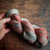 Malabrigo Rios RIO-262 Belinda Superwash Merino Worsted Yarn skein in multi-color shades of red, green, and gray on a wooden surface.