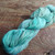 Malabrigo Rios RIO-264 Celestina Superwash Merino Worsted Yarn, soft turquoise and blue gradient, skein on wooden surface.