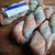 Malabrigo Rios RIO-267 Zahara Superwash Merino Worsted Yarn, skeins of multicolored yarn in shades of pink, blue, and orange, on a wooden surface.