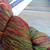 Malabrigo Rios yarn, Muted Rainbow color, skein of multicolored merino wool yarn in shades of red, orange, green, and yellow hues.