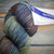 Malabrigo Rios Pocion yarn, jewel-tone worsted merino, multicolored skein with blue, green, orange, and purple hues, labeled as 139 Pocin.