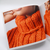Close-up of a vibrant orange knitted garment using Malabrigo Rasta super bulky yarn, highlighting the plush texture and stitch definition