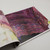 Malabrigo Pattern Book 11: Anniversario, showcasing vibrant multicolored patterns and designs in shades of pink, purple, and yellow, inside a colorful book.