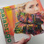 Malabrigo Pattern Book 7: Rasta In Brooklyn, colorful knitted scarf on blonde woman, vibrant hues, knitting patterns, Malabrigo branding on cover.