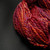 Skein of Spiced Berry Glow artisan yarn showing bulky weight thickness.