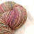 Multicolored skein of handspun sport/DK merino wool yarn, The Rogue Dye Lot Studio Variant HS-866B by Forever Winding Wool in pink, gold, and blue hues.