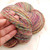 The Rogue Dye Lot Studio Variant HS-866B handspun sport DK merino wool yarn in a multicolored skein with pink, yellow, blue, and green hues.