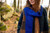 Woman wearing blue scarf from 52 Weeks of Accessories while wearing brown plaid shawl.  Outdoors in woodland setting.