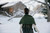 Green knitted cape or shawl on a person, winter scenery with snow-covered cabin and trees in background, showcasing 52 Weeks of Scarves pattern.