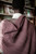 Woman wrapped in mauve knitted scarf, showcasing beautiful patterns and soft texture, perfect for year-round accessorizing and knitting inspiration.