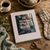Laine Publishing's 52 Weeks of Socks book cover surrounded by knitting materials, yarn, and a mug on a wooden surface with greenery.