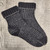 Black and white knitted sock, 52 Weeks of Socks Vol. II, featuring beautiful patterns for year-round knitting, on a wooden background.