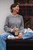 Woman wearing grey sweater from Knits to Wear: Effortless Patterns by Kutova Kika by Laine Publishing, sitting with coffee cup, casual outfit.