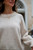 Woman wearing cream-colored knit sweater with ribbed neckline and cuffs from Knits to Wear: Effortless Patterns by Kutova Kika, Laine Publishing.