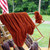 Squishy skein of Bittersweet burnt orange bulky merino wool hanging on an outdoor wooden yarn rack.