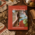 Weaving by Mary Maddocks hardback book on rustic wood, surrounded by yarn, fringed woven textiles, a wooden comb and scissors.