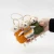 Hand holding three felted wool sheep ornaments in golden orange, orange and gray striped, and moss green knitted sweaters.