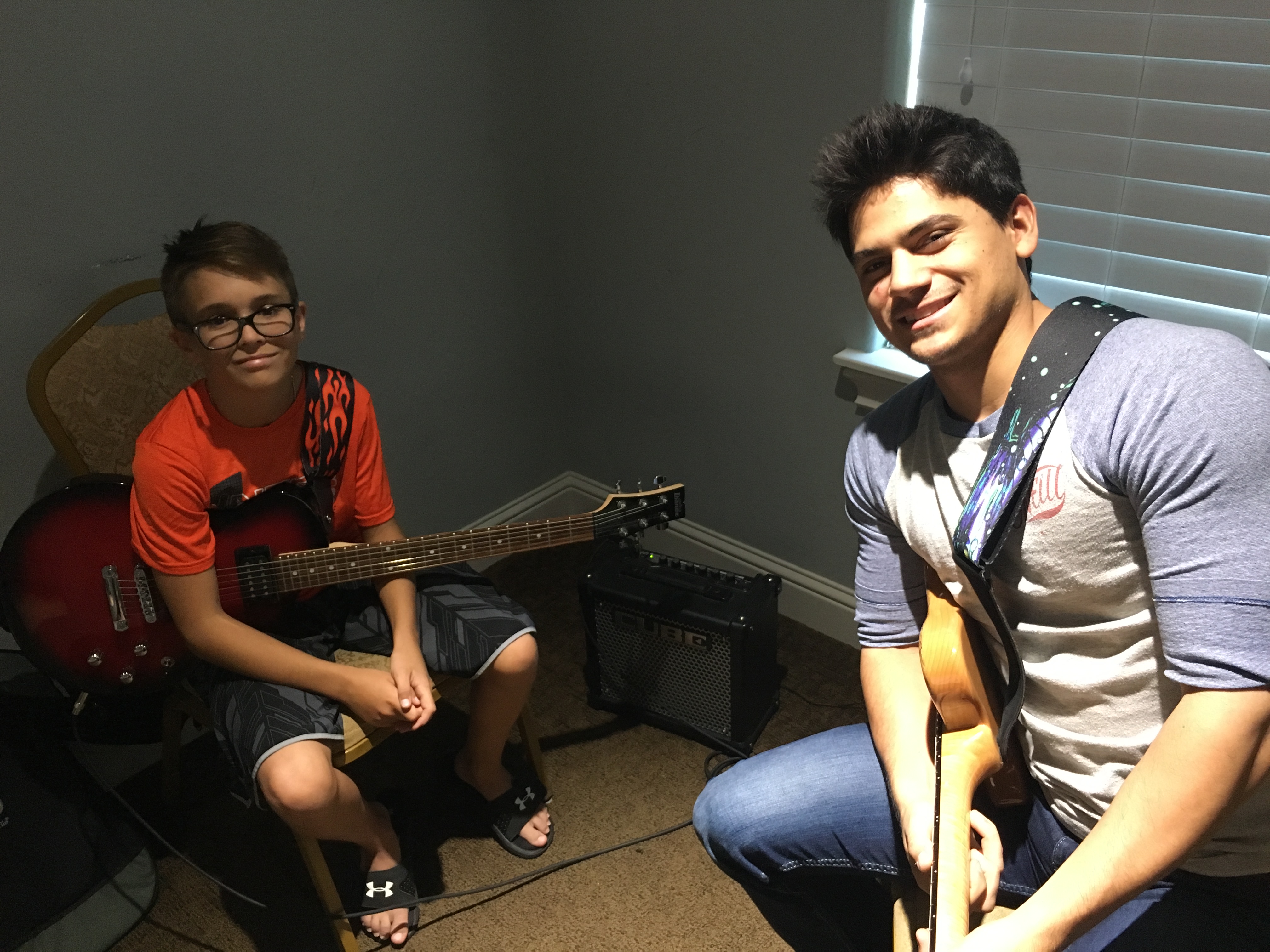 a couple of men sitting on a couch with a guitar