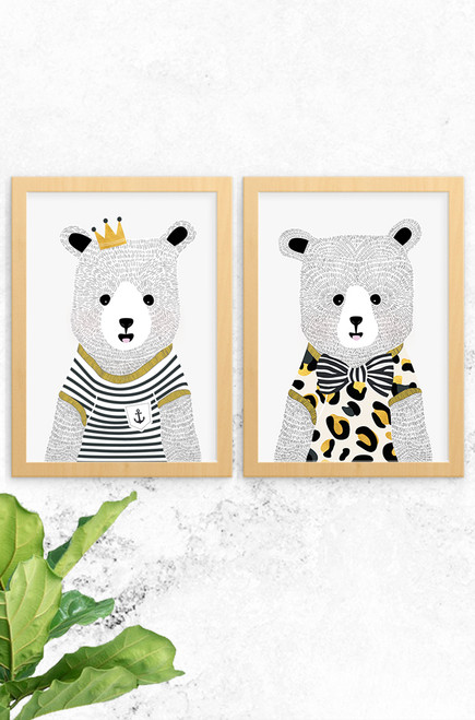 An image showing Luca Rose Designs 2 pack of Bear prints, named Noah and Ted. Both wear bold t-shirts, one with black and white stripes, the other with a striped bow tie and leopard print. Framed in an oak finish timber and mounted on a concrete wall. Illustrated and printed in Australia.