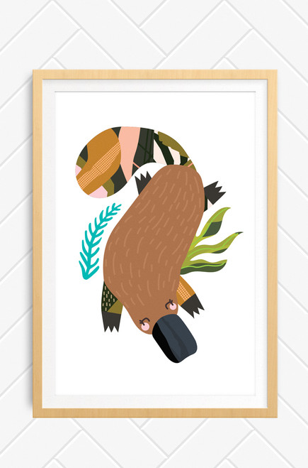 Brown platypus wall art print framed in an oak style wooden frame. The platypus has a patterned tail and legs with sweet eyes and pink cheeks. Illustrated digitally and printed in Australia.