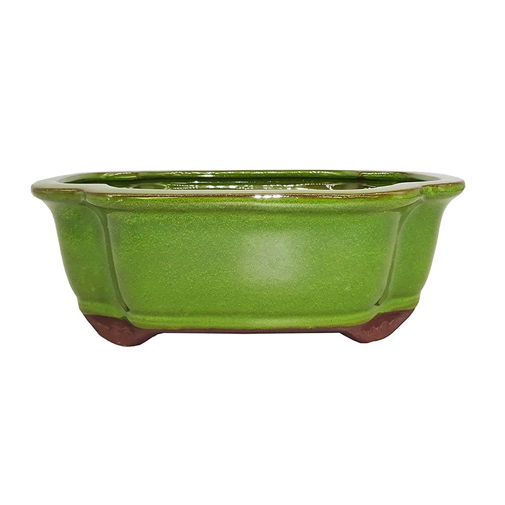 a green ceramic bowl with brown legs
