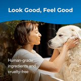 Woman bathing a large white dog and smiling. Text on image reads: ‘Look Good, Feel Good. Human-grade ingredients and cruelty-free.’