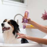 A black and white dog is picturedin a bathtub. A womans hands are shown squeezing Bio-Groom Silk into her hands to give the dog a bath.
