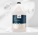 Gallon jug of Crown Coat Almond Grove All Purpose Conditioner surrounded by bubbles on a clean white background