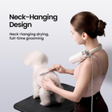 Woman wearing the Jirpet Harmony I Pet Neck Dryer while grooming a small white dog on a table, demonstrating the hands-free neck-hanging design Woman wearing the Jirpet Harmony I Pet Neck Dryer while grooming a small white dog on a table, demonstrating the hands-free neck-hanging design