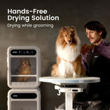 Groomer brushing a dog while another dog is dried hands-free inside the Jirpet F1 Pet Dryer Cabin