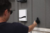 Man wearing sunglasses plugs an EV charging cable into a wall-mounted white Emporia Pro charger installed on the exterior of a house.