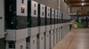 Row of EG4 12KPV hybrid inverters installed along a warehouse wall with stacked on top the of wallmount  batteries. 