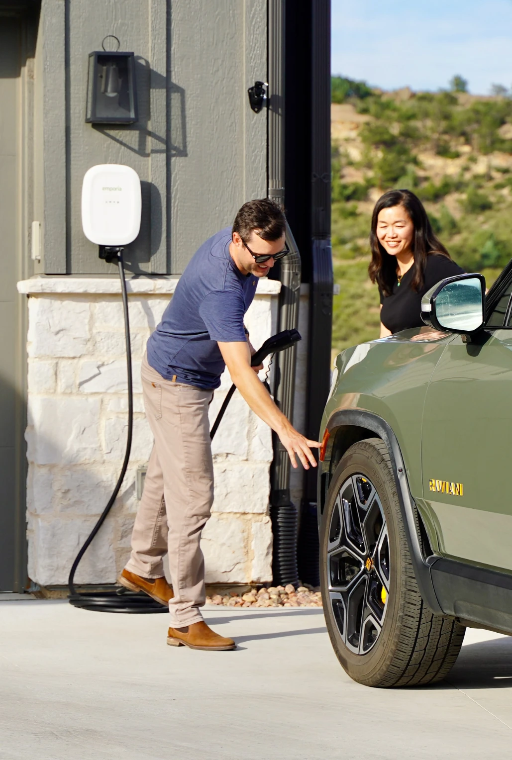 Two people charging vehicle in driveway with Emporia charger.