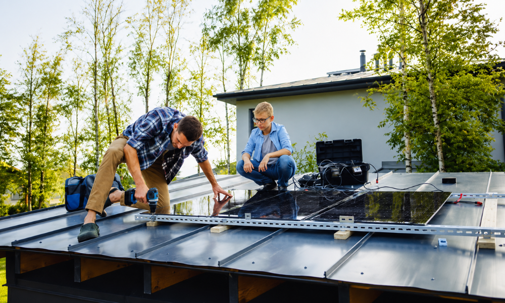 Father and son mounting solar panels on shed roof together.