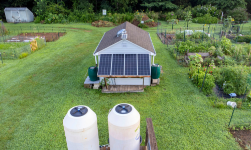 Large garden next to shed with solar panels and water collection tanks.