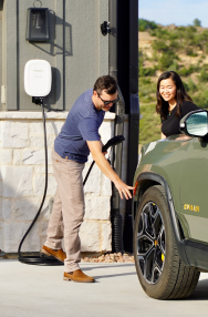 Two people charging vehicle in driveway with Emporia charger.